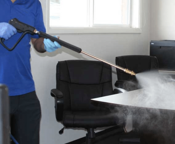Image of someone misting and office with the gun from the Prochem Micro-mist surface disinfecting system.